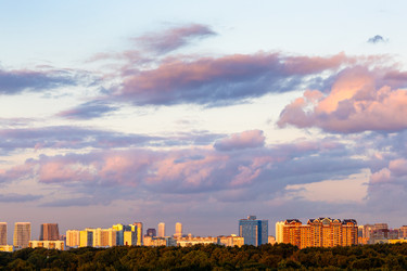 Темно-розовые облака в голубом закатном небе над городом - vale