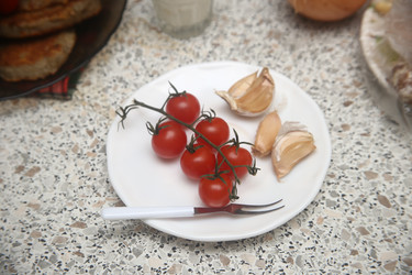 Вкусные красные помидоры черри с чесноком и вилкой на столе, крупный план - ZemLenik_photoclb