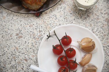 Вкусные красные помидоры черри с чесноком и сметаной на столе, крупный план - ZemLenik_photoclb