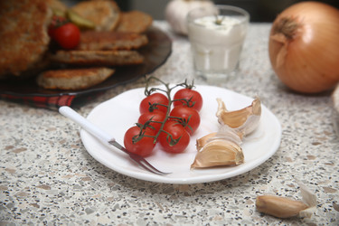 Вкусные красные помидоры черри с чесноком на столе, крупный план - ZemLenik_photoclb