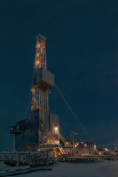освещенная буровая установка для добычи нефти и газа, работающая в суровых снежных условиях арктики во время зимней полярной ночи. концепция промышленной добычи и разведки энергии - Vkadimir