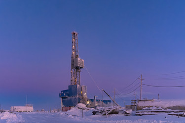 зимний вид работающей буровой установки для добычи нефти и газа, покрытой снегом, в суровых арктических условиях во время полярных сумерек. прекрасное пурпурное небо - Vkadimir