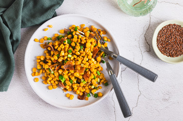 вкусная жареная кукуруза с беконом и зеленым луком на тарелке на столе вид сверху - Elena Rui