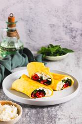 вкусные рулетики с фетой, жареным болгарским перцем и шпинатом на тарелке на столе вертикальный вид - Elena Rui