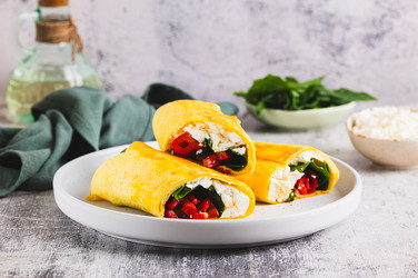вкусные рулетики с фетой, жареным болгарским перцем и шпинатом на тарелке на столе - Elena Rui
