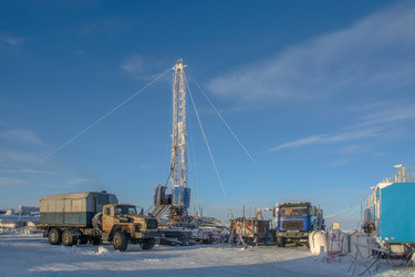 установка для капитального ремонта нефтяных и газовых скважин, работающая в суровых условиях арктической зимы. промышленный пейзаж с тяжелой техникой, заснеженной вечной мерзлотой и солнечным ясным полярным днем - Vkadimir