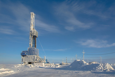 покрытая инеем буровая установка для бурения нефтяных и газовых скважин работает в экстремальных зимних условиях арктики в течение яркого полярного дня. окруженный глубоким снегом и ясным голубым небом - Vkadimir