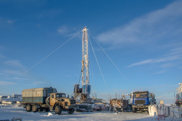 установка для капитального ремонта нефтяных и газовых скважин, работающая в суровых условиях арктической зимы. промышленный пейзаж с тяжелой техникой, заснеженной вечной мерзлотой и солнечным ясным полярным днем - Vkadimir