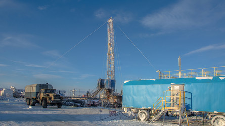 установка для капитального ремонта нефтяных и газовых скважин, работающая в суровых условиях арктической зимы. промышленный пейзаж с тяжелой техникой, заснеженной вечной мерзлотой и солнечным ясным полярным днем - Vkadimir