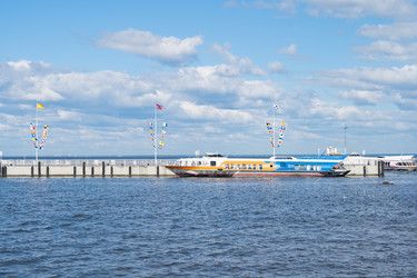 Широкий горизонтальный вид пассажирских паромов на подводных крыльях, пришвартованных к причалу в Петергофе, Санкт-Петербург. Живописный морской транспортный фон над спокойной водой Невской губы под голубым летним небом с копировальным пространством - IKvyatkovskaya