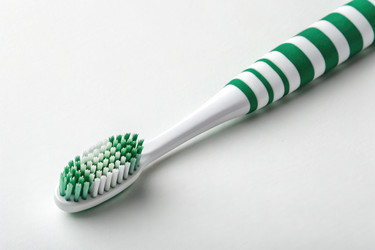 зубная щетка в зеленую и белую полоску на чистой поверхности - RomanZ