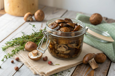 вкусные домашние маринованные грибы в стеклянной банке на деревянном столе - RomanZ