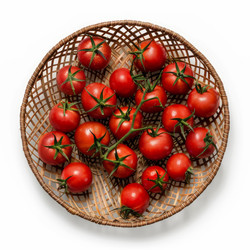 Fresh red cherry tomatoes resting in a woven basket - yliv