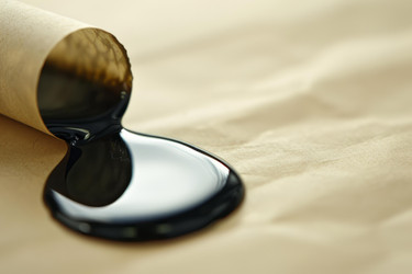 Barrel of crude oil spilling on brown paper background - yliv