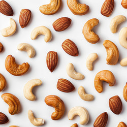 Roasted cashew nuts and almonds forming a pattern on white background - yliv