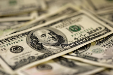 Pile of one hundred dollar bills is laying on a table, with the front and center bill showing benjamin franklin looking upwards - yliv