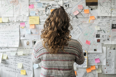 Project manager planning looking at notes on wall in office - yliv