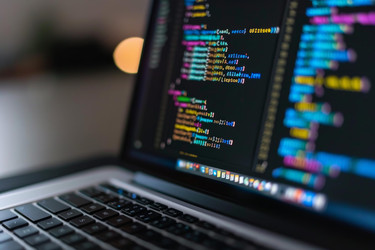 Open laptop displaying lines of code on the screen in a dark room - yliv