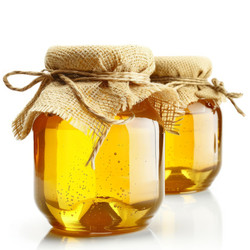 Two glass jars containing delicious golden honey with rustic fabric lids on white background - yliv