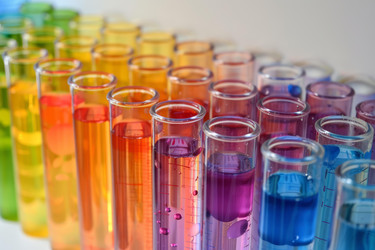Scientist analyzing test tubes filled with colorful chemical liquid for scientific experiment - yliv