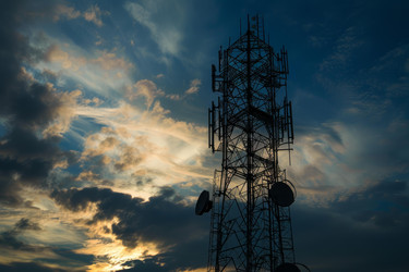 Telecommunication tower is silhouetted against a vibrant sunset sky - yliv
