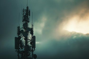 Lone telecommunication tower is standing tall against a dramatic sky at sunset, symbolizing the advancement of technology - yliv