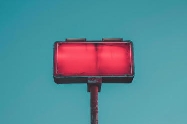 Glowing red signage standing tall against a vibrant teal sky, creating a striking visual contrast - yliv