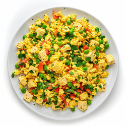 Vegan tofu scramble with vegetables and herbs, healthy plant based breakfast on white plate - yliv