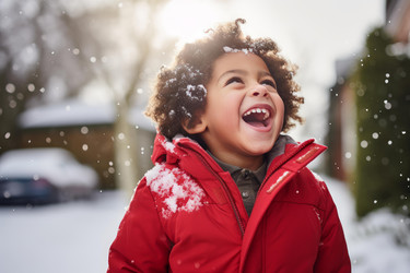 Young child with a red winter coat laughing and enjoying the falling snow - yliv