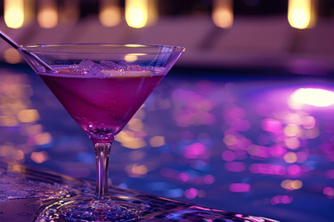 Vibrant purple cocktail sits poolside, enhancing the ambiance of a luxurious nightlife scene - yliv