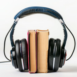 Black headphones holding together two books on white background for audiobook concept - yliv