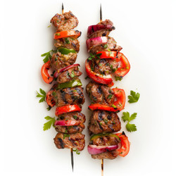 Two skewers with juicy grilled meat, red onion, green pepper and tomato pieces seasoned with fresh herbs - yliv
