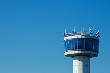 Airport control tower overseeing air traffic on a sunny day with vibrant blue skies - yliv