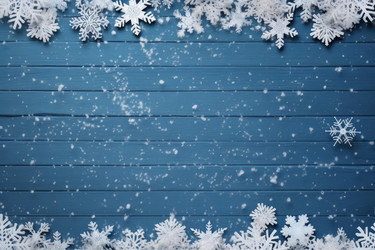 Snowflakes falling on blue wooden background creating winter christmas scene - yliv