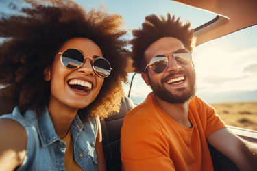 Young couple laughing and enjoying road trip in convertible car - yliv