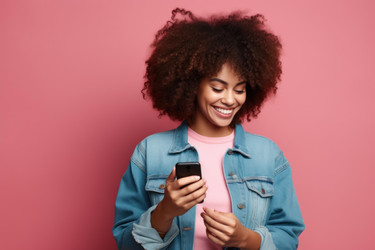 Cheerful young woman using smartphone on pink background - yliv