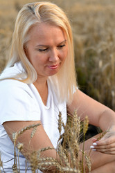 женщина спокойно сидит на золотистом пшеничном поле во время заката, размышляя о жизни и красоте природы среди высоких стеблей - VetalanaS