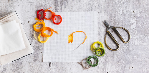 Cross-stitch—a trendy analog hobby—with a kit on the table top view web banner - Elena Rui