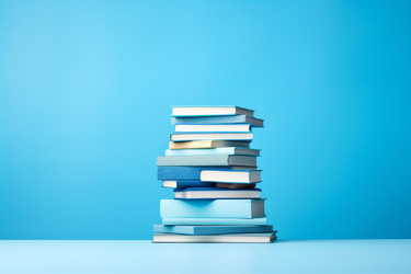 стопка книг, образующих башню знаний на синем фоне - yliv