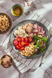 полезный салат из тунца с белой фасолью, сыром фета, помидорами, редисом и зеленью на мраморном столе - Irrin0215