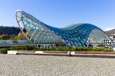 современный стеклянный мост мира через реку кура в тбилиси, грузия - gumbao