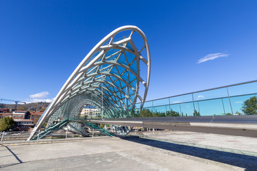 современный стеклянный мост мира через реку кура в тбилиси, грузия - gumbao