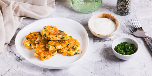 аппетитные оладьи, приготовленные из вареных яиц, зеленого лука и сыра, на тарелке на веб-баннере "стол" - Elena Rui