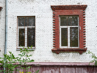 Два окна с решетками на фасаде старого кирпичного здания - raregarden