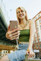 Портрет улыбающейся женщины, делающей селфи на смартфоне на открытом воздухе - SeventyFour