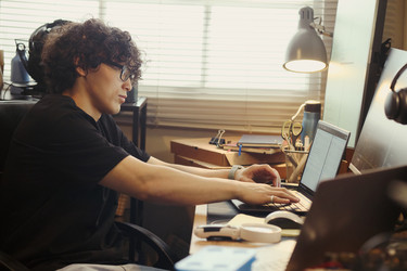 Азиат программирует на ноутбуке за столом домашнего офиса - DragonImagesAsia