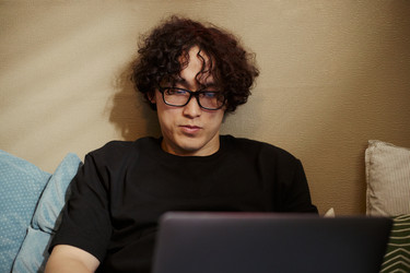 Азиат в очках работает дома за ноутбуком - DragonImagesAsia