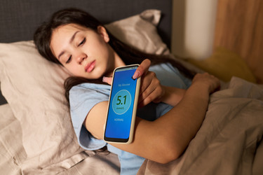 Девочка-подросток в постели уровня глюкозы сканирование со смартфона Приложение - Pressmaster