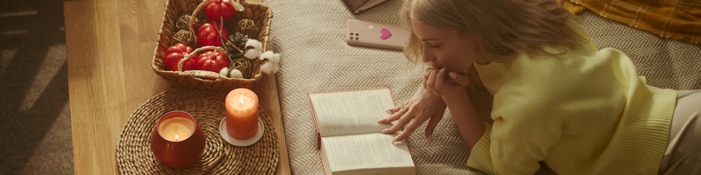 Женщина читает книгу на полу в уютной осенней домашней атмосфере - DragonImagesAsia