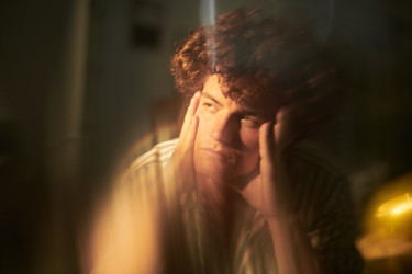 Задумчивый Мужчина, держащий голову в руках и выражающий умственное напряжение - Pressmaster